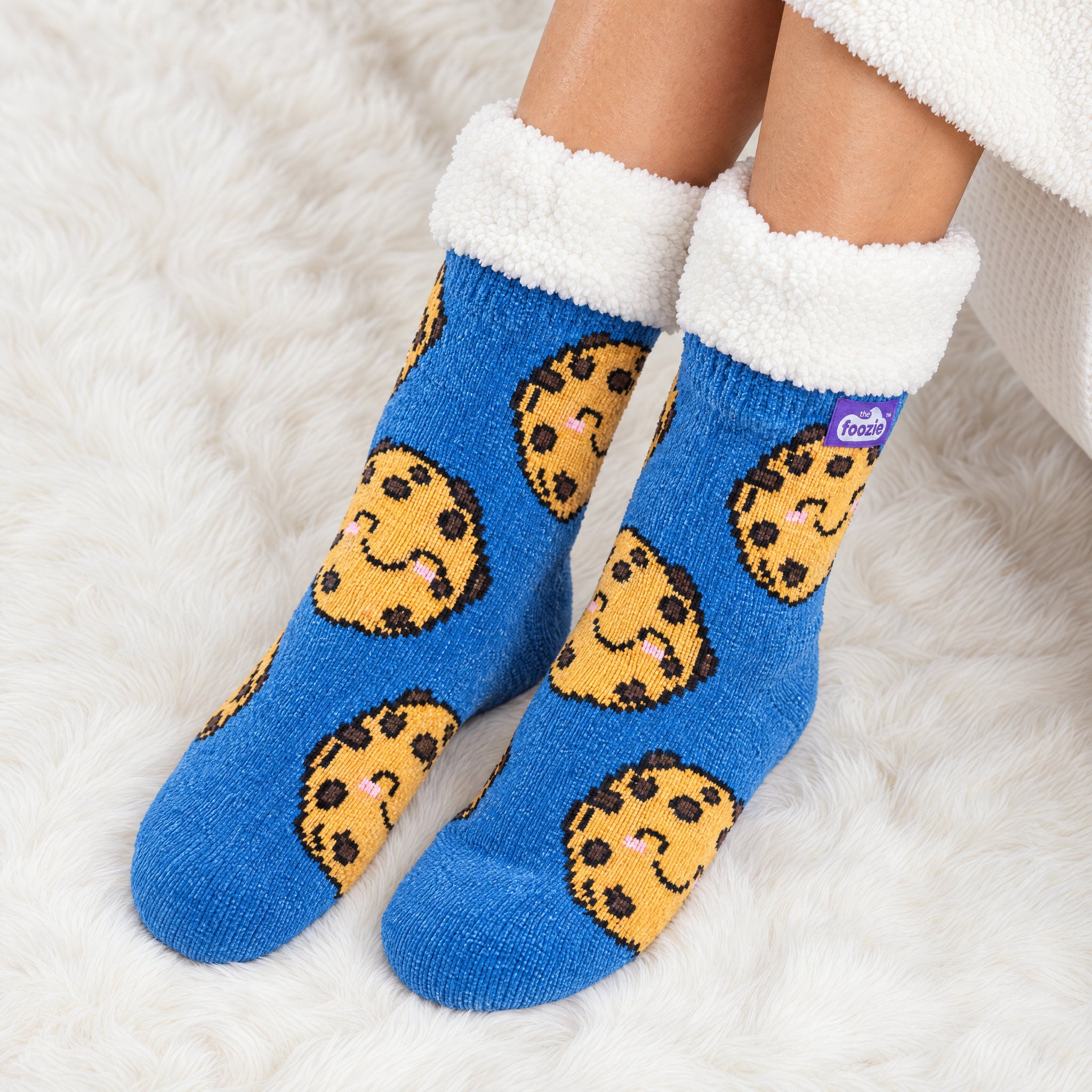 The Foozie™ Cookie slipper socks, on a fluffy rug