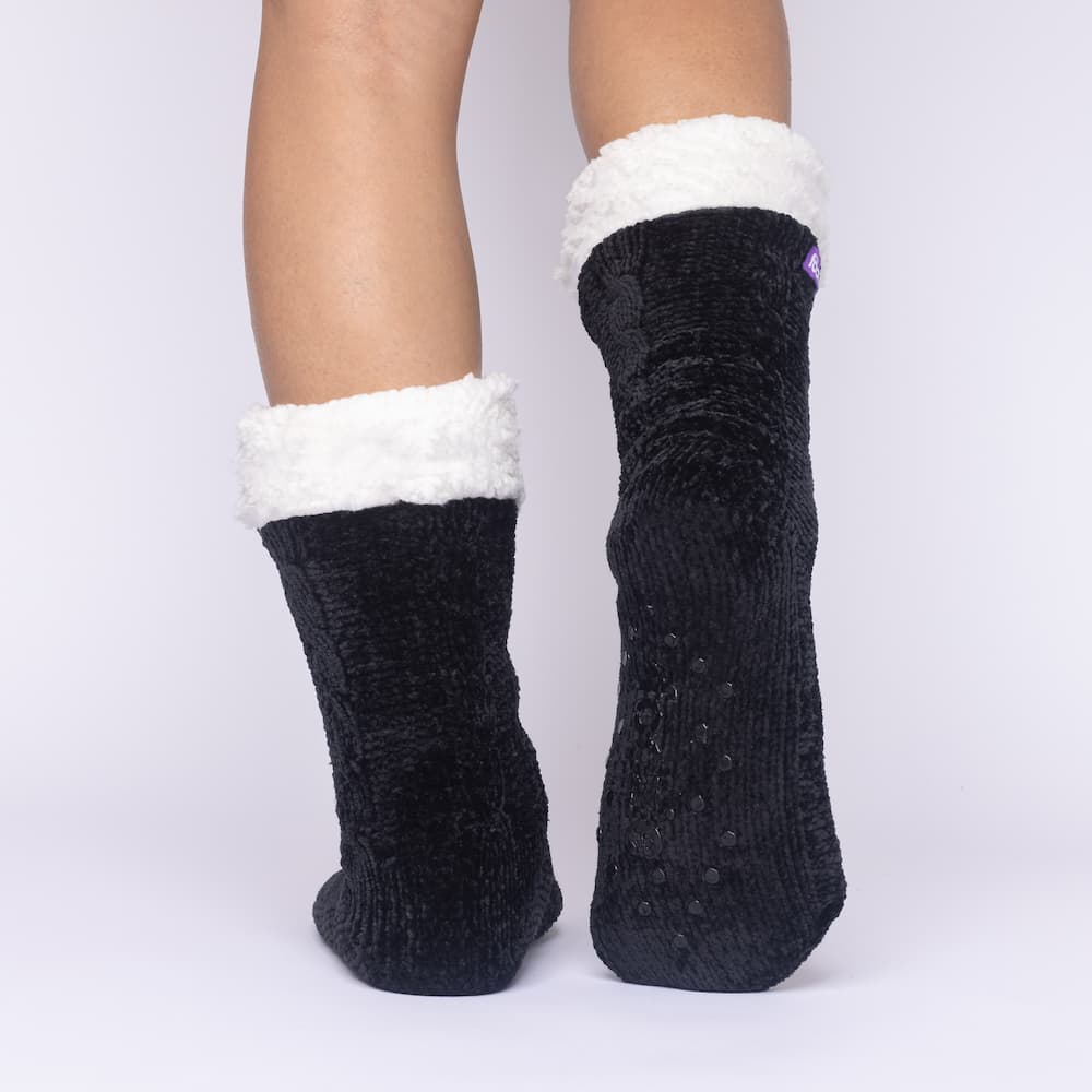 The Foozie™ in Black, back view with one foot raised to show the non-slip grips on the sole