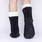 The Foozie™ in Black, back view worn by a man in Large with one foot raised to show the non-slip grips on the sole