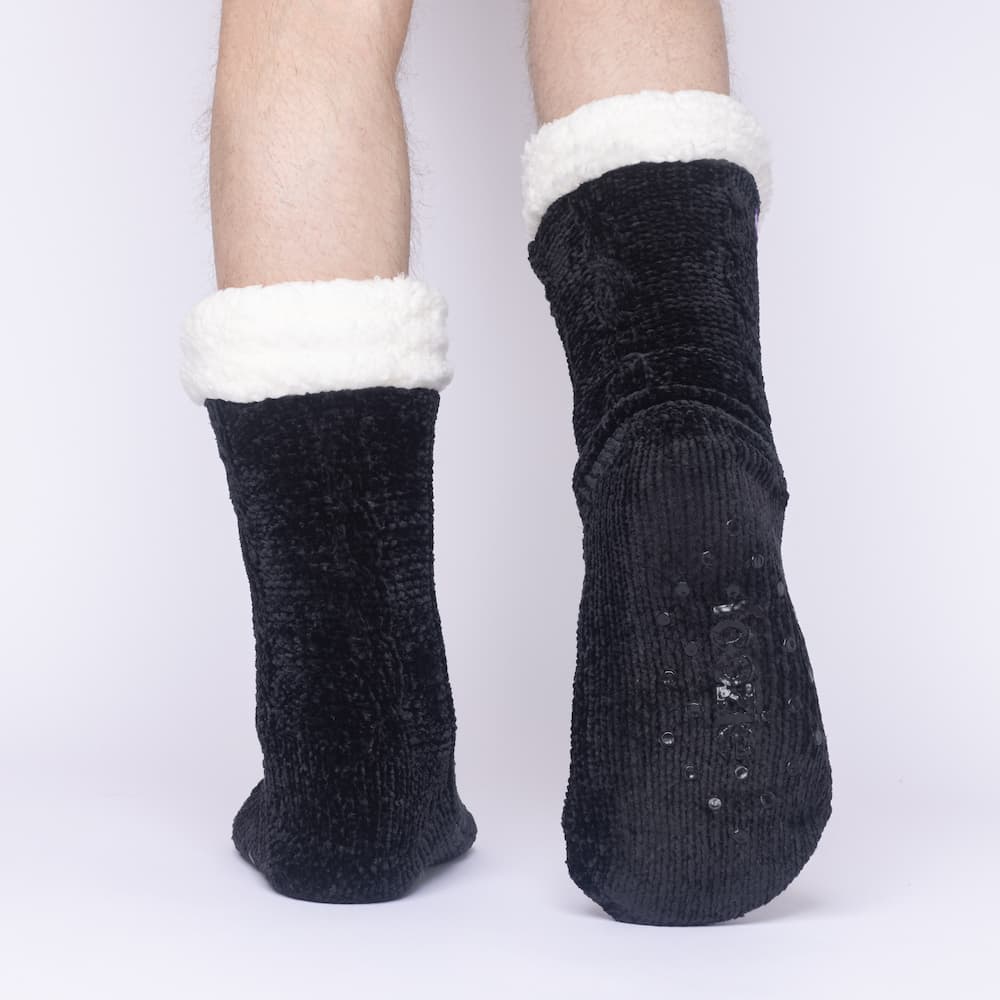 The Foozie™ in Black, back view worn by a man in Large with one foot raised to show the non-slip grips on the sole